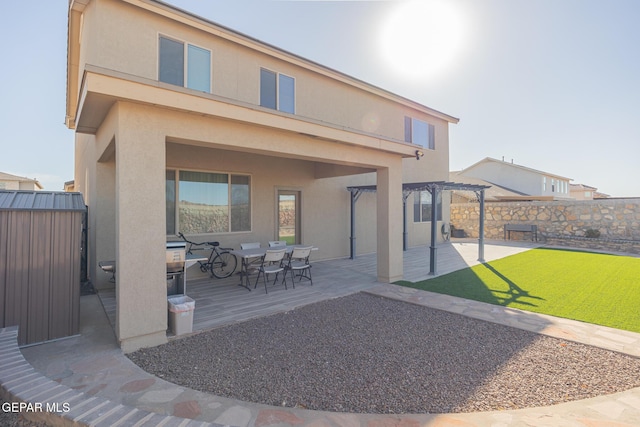 rear view of house with a patio, fence private yard, a yard, stucco siding, and a pergola