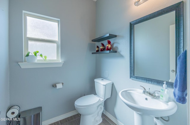 bathroom featuring baseboards, a sink, and toilet