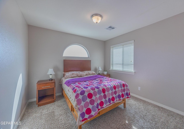 bedroom with baseboards, visible vents, and light colored carpet