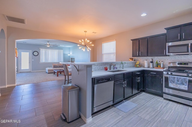 kitchen featuring visible vents, appliances with stainless steel finishes, open floor plan, a sink, and a peninsula