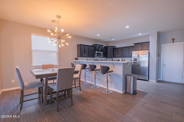 dining space featuring baseboards, visible vents, wood finished floors, a chandelier, and recessed lighting