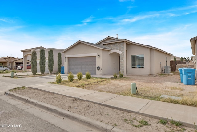 view of front of home with stucco siding, an attached garage, central AC unit, stone siding, and driveway