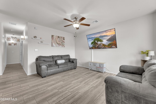 living room featuring a ceiling fan, wood tiled floor, visible vents, and baseboards