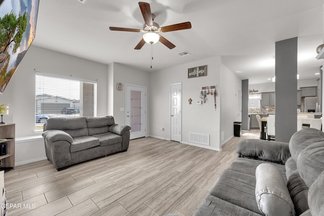 living area with light wood-type flooring, visible vents, and baseboards