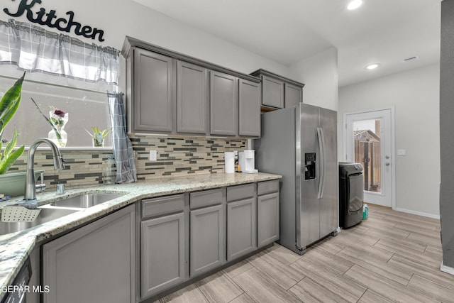 kitchen with stainless steel appliances, a sink, decorative backsplash, and gray cabinetry