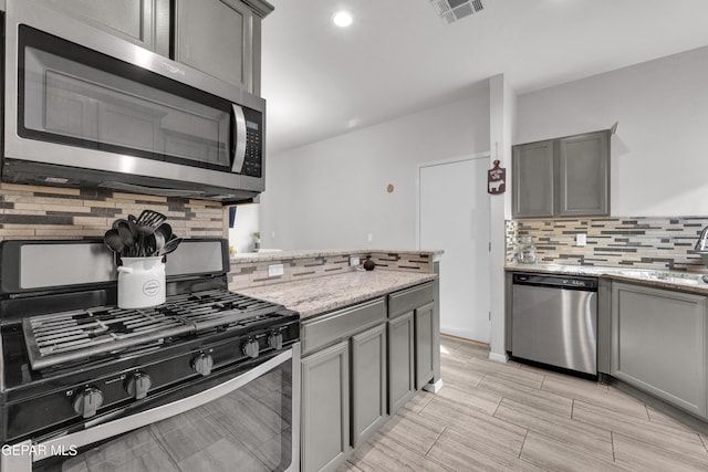 kitchen featuring tasteful backsplash, visible vents, stainless steel appliances, and gray cabinetry