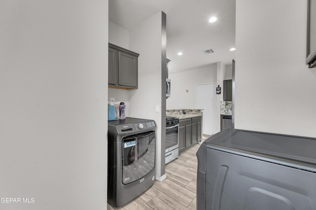 clothes washing area featuring washer / dryer, wood tiled floor, visible vents, and recessed lighting