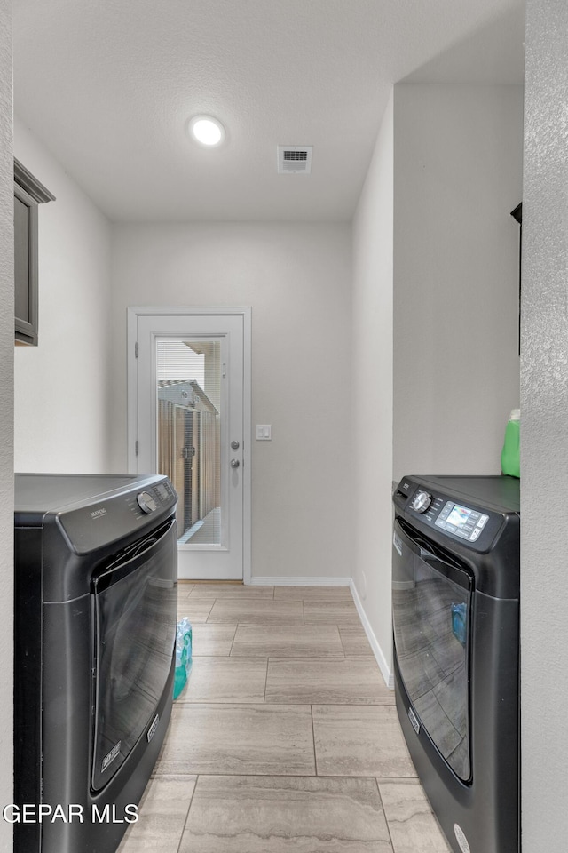 laundry area featuring laundry area, visible vents, baseboards, independent washer and dryer, and wood tiled floor