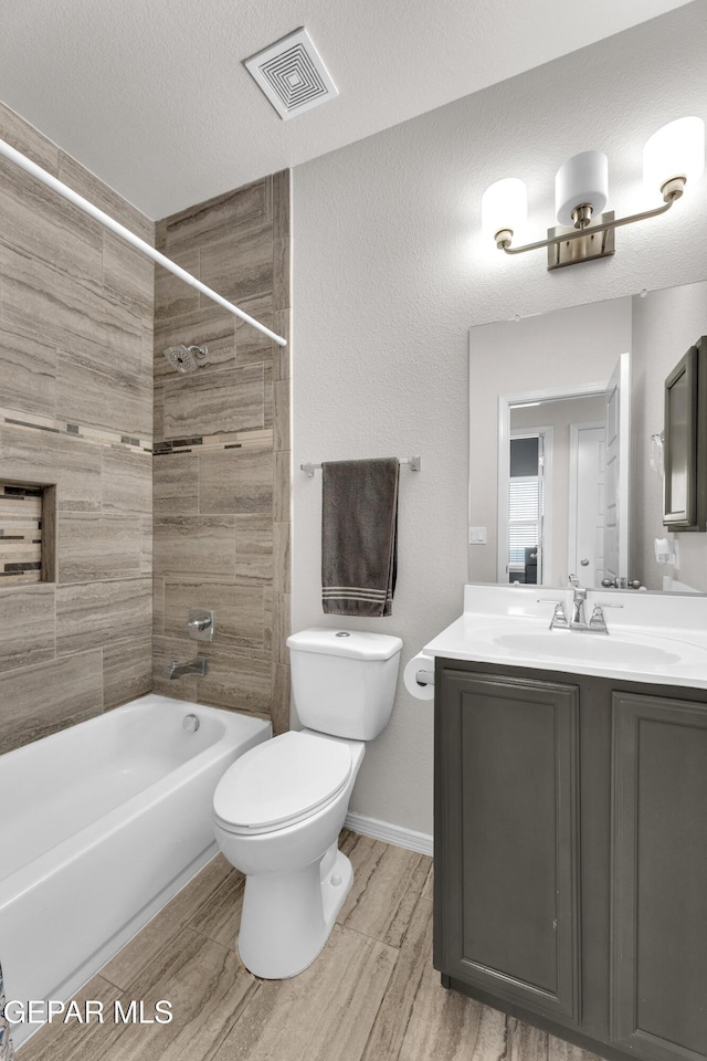 bathroom featuring a textured ceiling, shower / bathtub combination, toilet, vanity, and visible vents