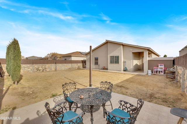 rear view of property featuring outdoor dining space, a patio area, a fenced backyard, and stucco siding