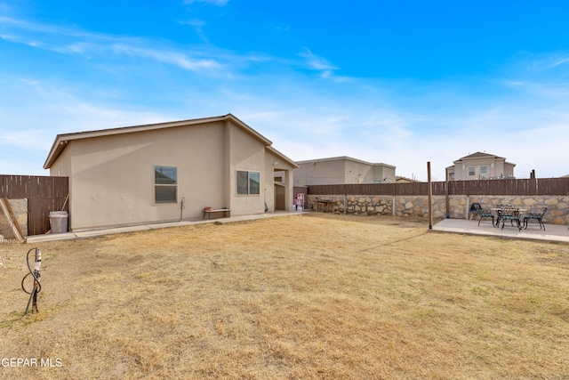 back of house with a patio area, a lawn, a fenced backyard, and stucco siding