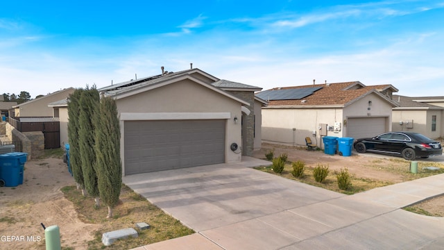 ranch-style house featuring solar panels, stucco siding, concrete driveway, an attached garage, and fence