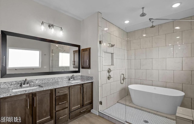 bathroom featuring double vanity, a sink, a freestanding bath, and a stall shower