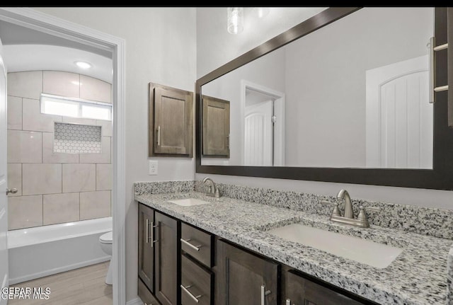 full bath featuring double vanity, toilet, a sink, and wood finished floors