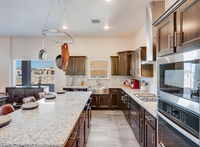 kitchen with tasteful backsplash, visible vents, stainless steel gas cooktop, and light stone countertops