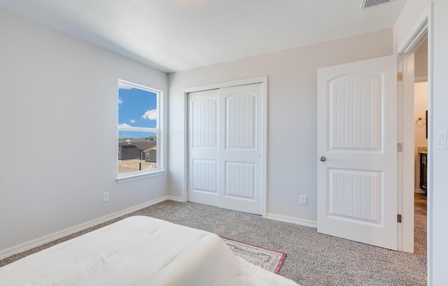 carpeted bedroom featuring a closet, visible vents, and baseboards