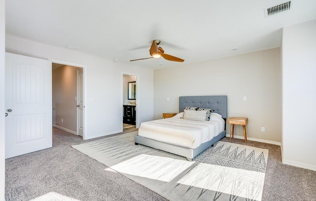 carpeted bedroom featuring a ceiling fan, visible vents, baseboards, and ensuite bathroom