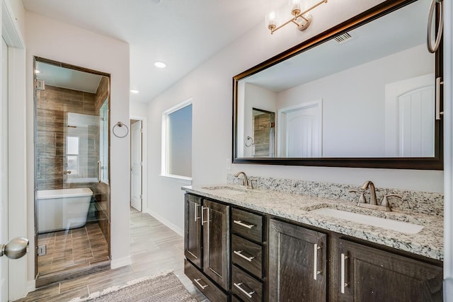 full bath with a stall shower, wood finish floors, a sink, and double vanity