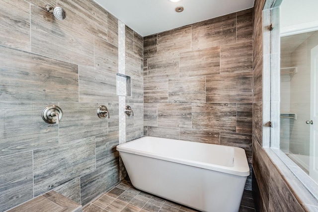 bathroom with a tile shower, tile walls, and a freestanding bath