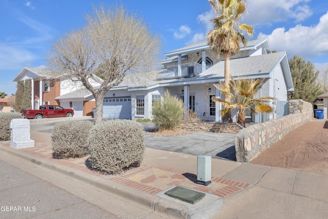 view of front of house with decorative driveway, a balcony, and an attached garage