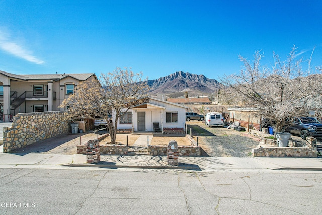 view of front of house featuring fence, a mountain view, and concrete driveway