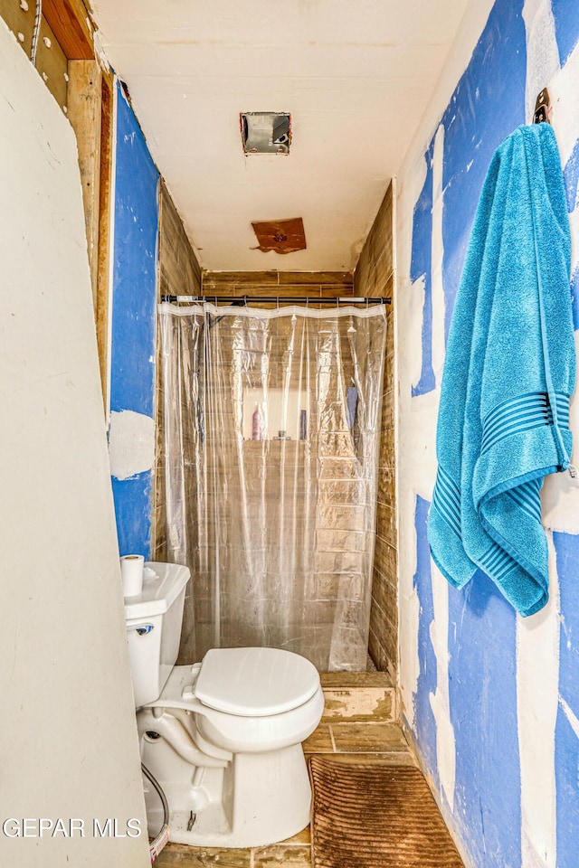 full bathroom featuring toilet and a tile shower