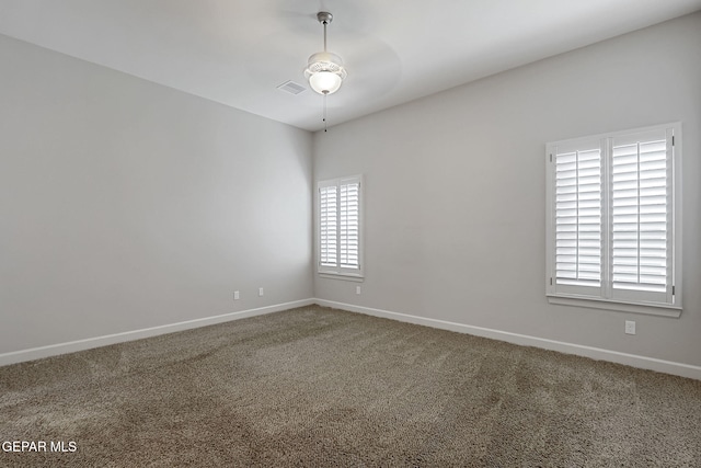 carpeted spare room featuring a ceiling fan, visible vents, and baseboards