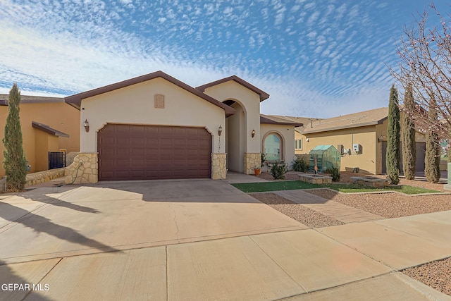 mediterranean / spanish-style home featuring driveway, stone siding, an attached garage, and stucco siding