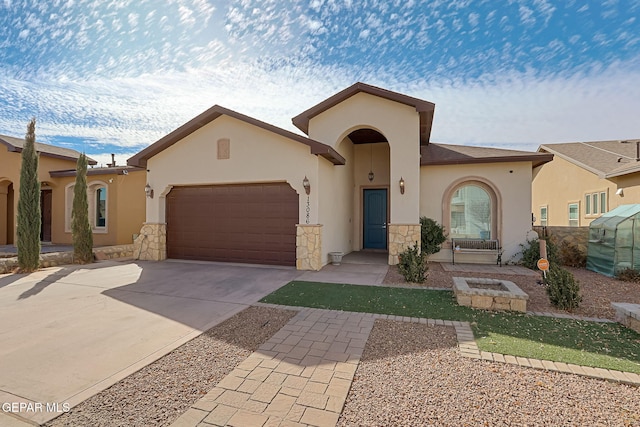 mediterranean / spanish-style house with stone siding, concrete driveway, an attached garage, and stucco siding