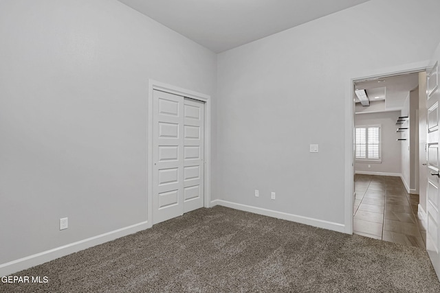 unfurnished bedroom with carpet floors, tile patterned flooring, a closet, and baseboards