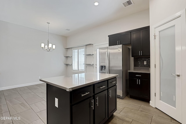 kitchen with visible vents, light countertops, hanging light fixtures, stainless steel fridge with ice dispenser, and tasteful backsplash