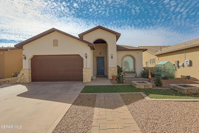 mediterranean / spanish home featuring a garage, concrete driveway, stone siding, and stucco siding