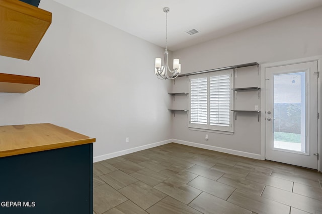 unfurnished dining area featuring an inviting chandelier, plenty of natural light, visible vents, and baseboards