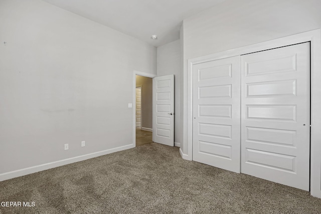 unfurnished bedroom featuring lofted ceiling, a closet, baseboards, and carpet flooring