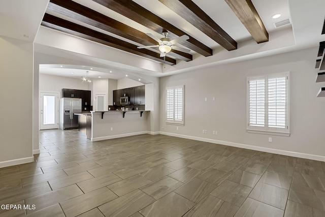 unfurnished living room featuring a ceiling fan, beam ceiling, and baseboards