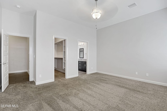 unfurnished bedroom with carpet, a closet, a spacious closet, and baseboards