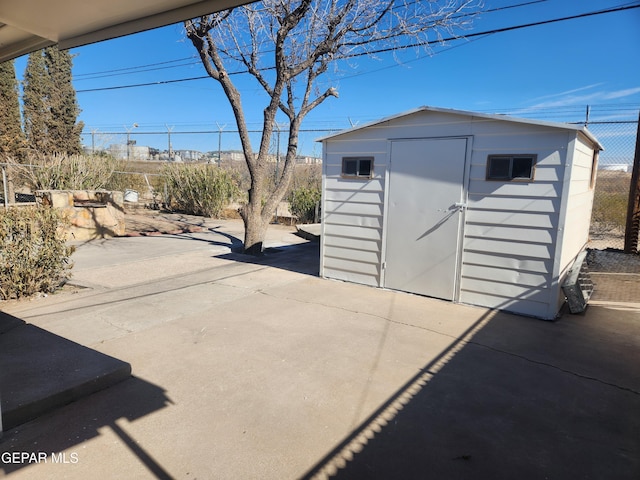 view of patio / terrace with a storage unit, an outdoor structure, and fence