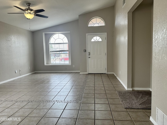 foyer entrance with lofted ceiling, light tile patterned flooring, a textured wall, and visible vents