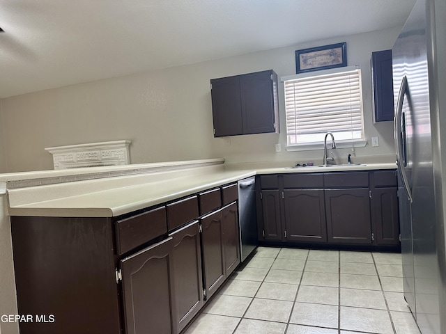 kitchen featuring light tile patterned flooring, a peninsula, a sink, light countertops, and appliances with stainless steel finishes