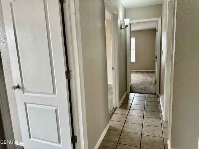 corridor with light tile patterned floors and baseboards