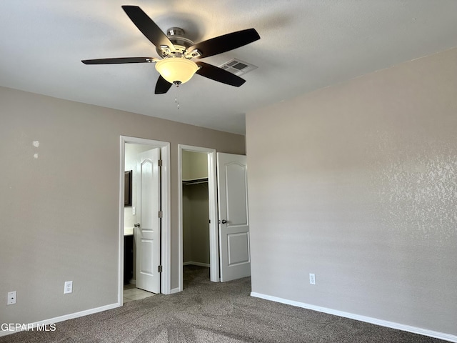 unfurnished bedroom featuring baseboards, visible vents, a walk in closet, carpet flooring, and a closet