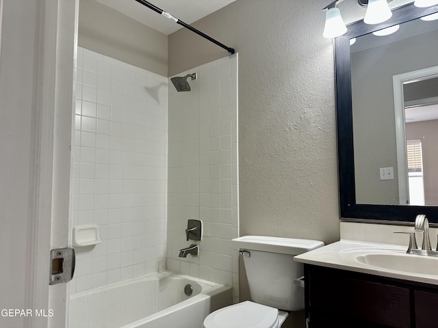 bathroom with toilet, vanity, shower / washtub combination, and a textured wall