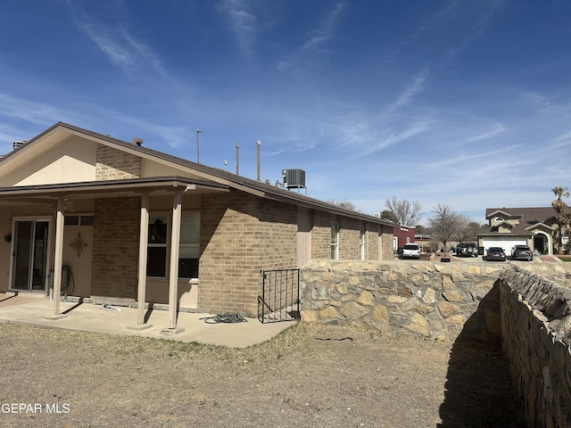 view of side of home with cooling unit and brick siding