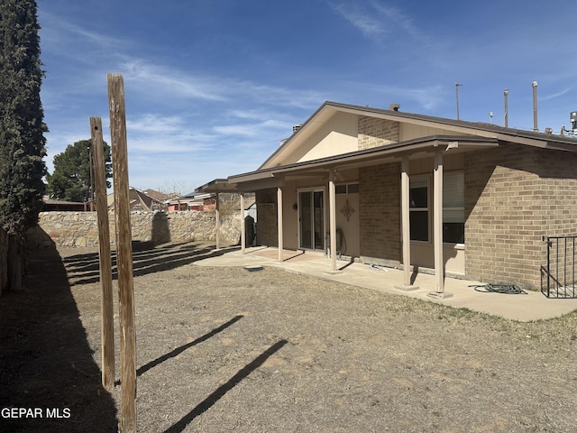 rear view of property featuring brick siding, a patio area, and fence