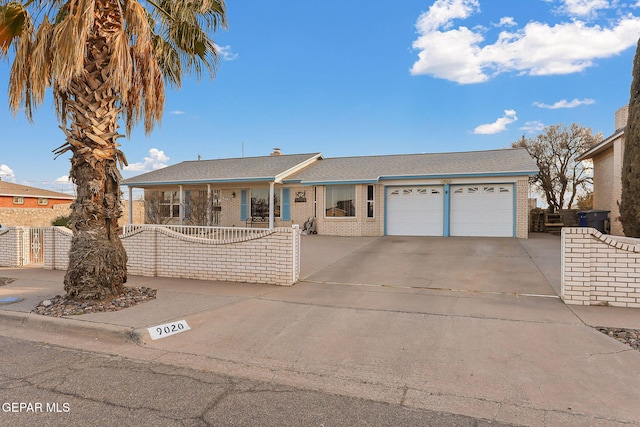 ranch-style house with a garage, concrete driveway, brick siding, and fence