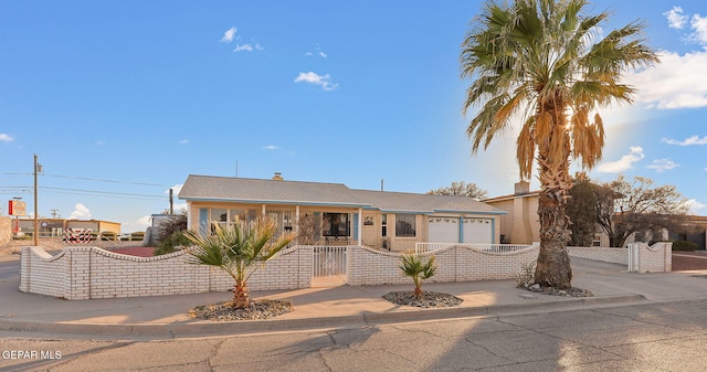 single story home with a fenced front yard, a gate, driveway, and an attached garage