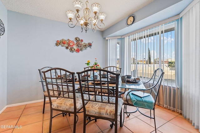 tiled dining area featuring a notable chandelier, a textured ceiling, and baseboards