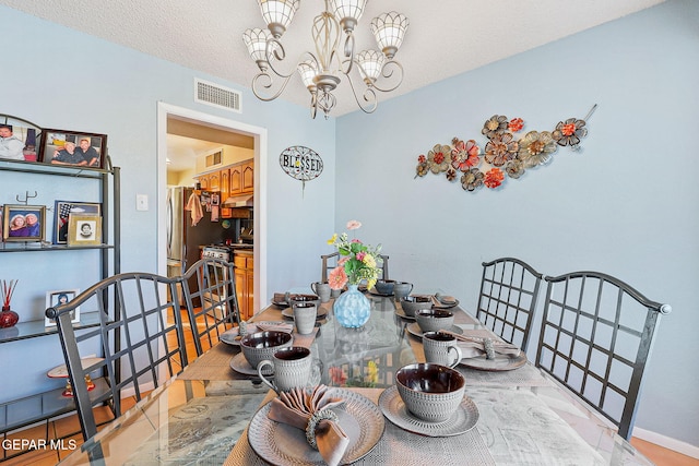 dining space with visible vents, a chandelier, and a textured ceiling