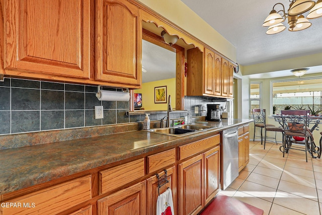 kitchen featuring light tile patterned floors, stainless steel dishwasher, a sink, and brown cabinets