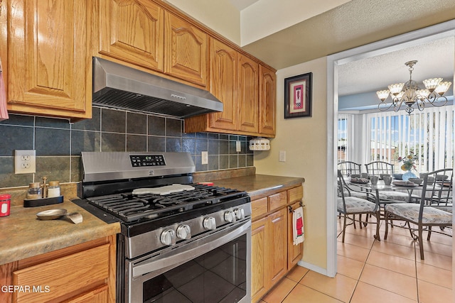 kitchen with light tile patterned floors, decorative backsplash, ventilation hood, a chandelier, and gas stove